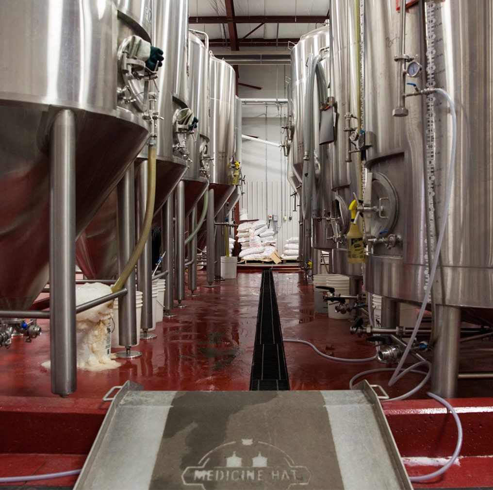 Medicine Hat brewery tanks in two rows with red flooring.