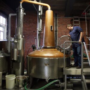A man looks into the door window of distillery tank.