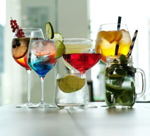 A table filled with different colours of drinks, each drink has a fruit inside.